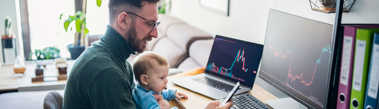 Father and son looking at computer and phone in home office