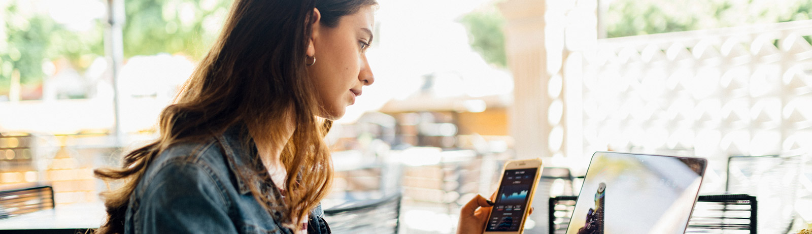 Young woman using laptop and phone in restaurant